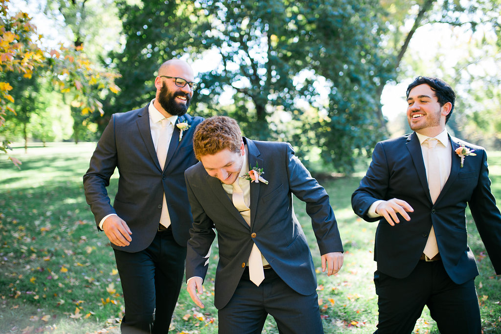 two groomsmen and a groom laughing and messing around
