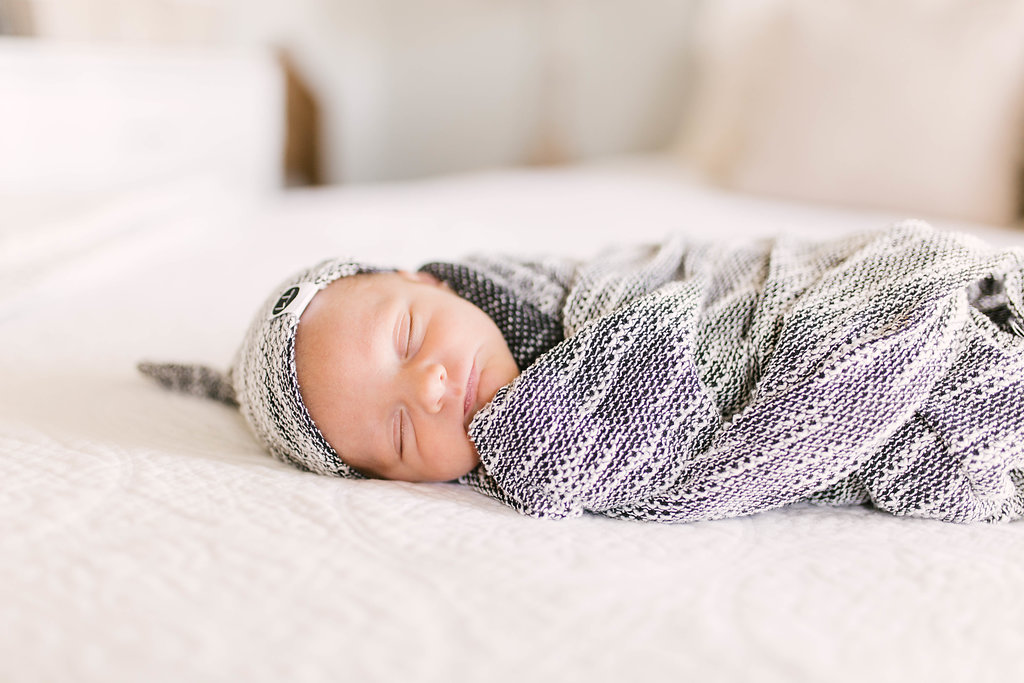 a newborn baby boy swaddled in a gray blanket