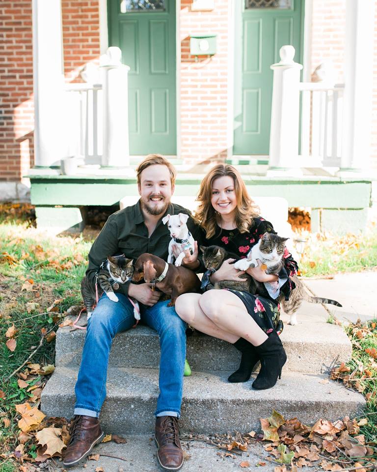 a couple on their porch steps with their three cats and two dogs