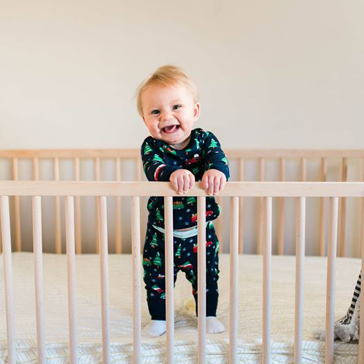8 month old ellis holding onto the crib, standing up