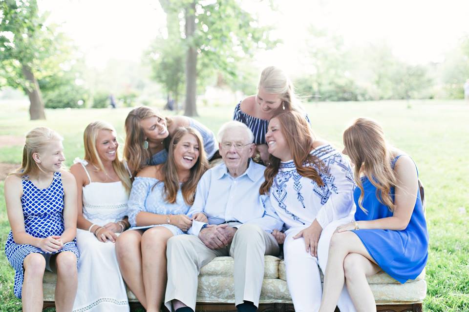 a granpda with his seven grand daughters laughing