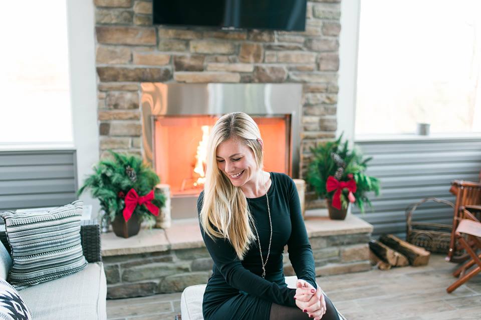 a woman laughing and looking to the left in her home with a fireplace in the background
