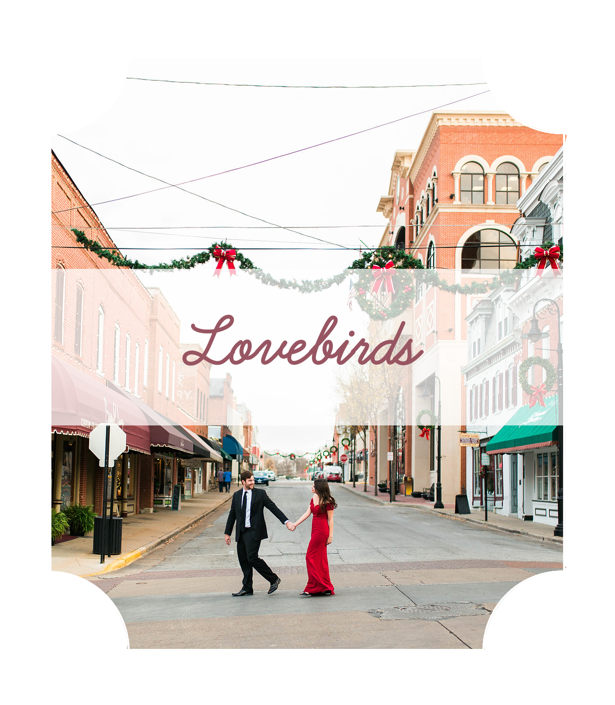 a couple, a woman in a long red dress, and a man in a suit, walking across a street with Christmas decorations all around