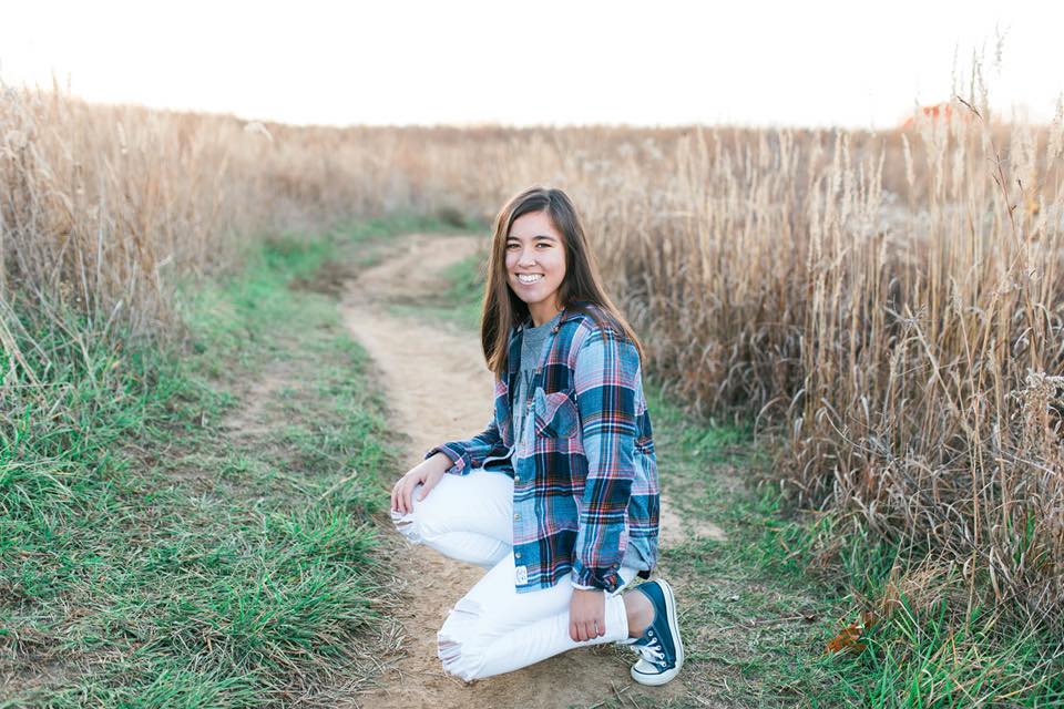 a senior shoot of a girl kneeling in a field of wheat