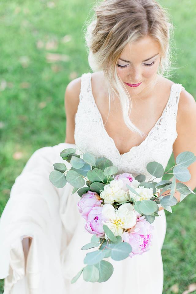 a blonde bride looking down with a eucalyptus and rose bouquet