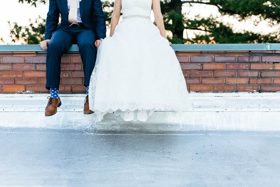 the legs of a bride and groom who are sitting on a red brick wall